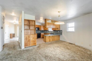 Kitchen with open shelves, light carpet, a sink, a peninsula, and black appliances