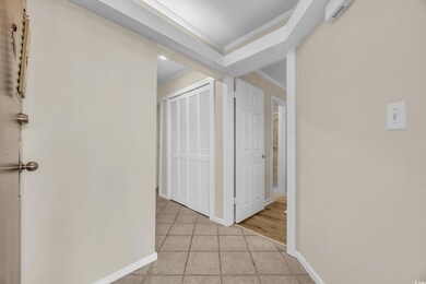 Hall with crown molding and light tile patterned f