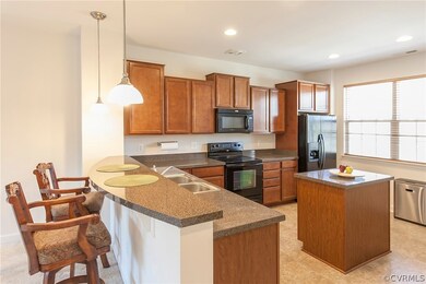 Kitchen with bar-height countertop, island, recessed lighting, and pendant lighting.