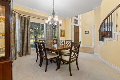 The dining room has carpet, crown molding, bay windows and chandelier.