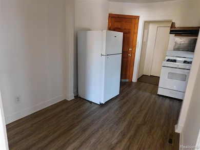 Kitchen featuring white appliances, dark wood-style flooring, and brown cabinetry