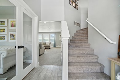 Staircase featuring a towering ceiling, wood finished floors, french doors, and recessed lighting