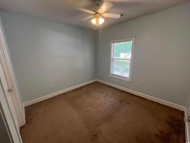 Empty room with ceiling fan and dark colored carpet