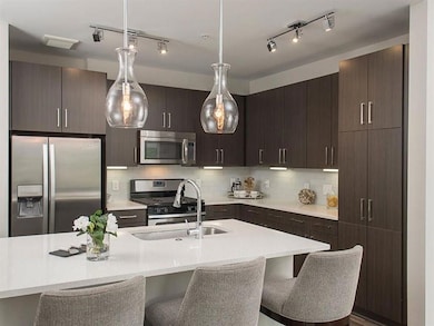 Kitchen featuring tasteful backsplash, hanging light fixtures, track lighting, stainless steel appliances, and a breakfast bar area