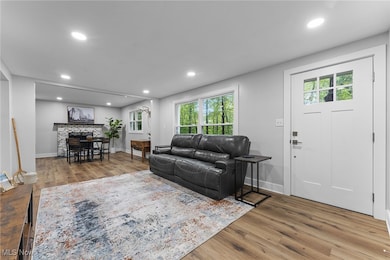 Additional view of the living room with flow to the dining area featuring neutral decor and front door