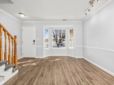 Entrance foyer with stairway, crown molding, wood finished floors, and a textured ceiling