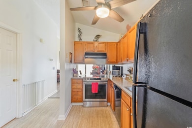 Kitchen featuring freestanding refrigerator, electric stove, dishwashing machine, under cabinet range hood, and light wood finished floors