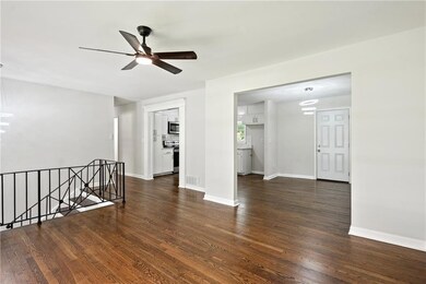 Empty room with a chandelier, dark wood finished floors, and a ceiling fan