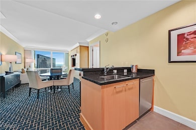 Kitchen with crown molding, stainless steel appliances, light brown cabinetry, a peninsula, and dark tile patterned floors
