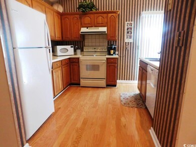 Kitchen featuring white appliances, wallpapered wa