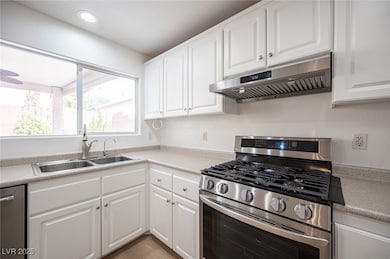Kitchen featuring stainless steel appliances, white cabinets, under cabinet range hood, light countertops, and recessed lighting