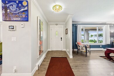 Entrance foyer featuring crown molding, baseboard heating, and light wood-type flooring