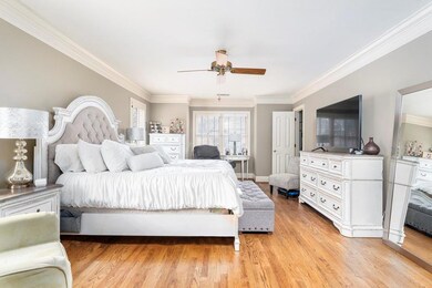 Bedroom featuring ornamental molding, light wood-style flooring, and a ceiling fan