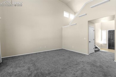 Carpeted spare room featuring high vaulted ceiling