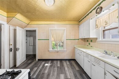 Kitchen with LVT flooring, Stove and refrigerator and white cabinets with tiled walls