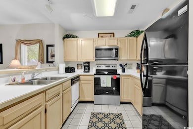 Kitchen with appliances with stainless steel finishes, light brown cabinetry, light countertops, and light tile patterned floors