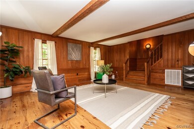 Living room with beam ceiling, wood walls, and lig