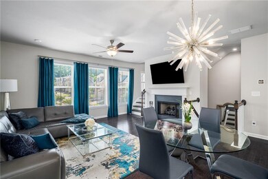 Living area with dark wood-style floors, a chandelier, a ceiling fan, a fireplace, and stairway