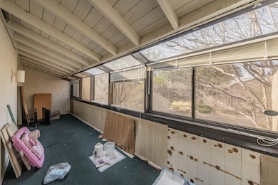 Unfurnished sunroom featuring beamed ceiling
