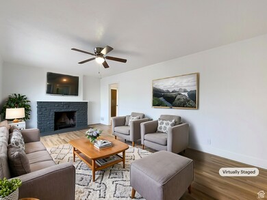 Living room featuring wood finished floors, a fireplace, and ceiling fan