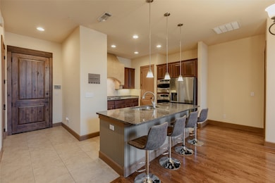 Kitchen featuring dark stone counters, a breakfast bar, pendant lighting, an island with sink, and appliances with stainless steel finishes