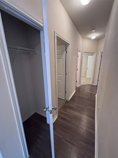 Corridor featuring dark wood-style floors and bas
