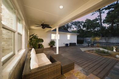 Relax on the expansive covered patio featuring a ceiling fan and inviting lounge area, with seamless flow to the backyard pool and landscaped garden beds. The custom deck adds space for entertaining or quiet evenings, all surrounded by thoughtfully placed greenery for added privacy.