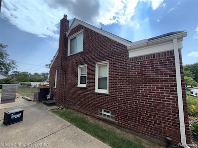View of home's exterior with brick siding, a chimney, and a gate