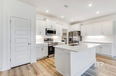 Kitchen featuring appliances with stainless steel finishes, white cabinets, a center island with sink, light hardwood / wood-style floors, and decorative backsplash