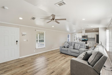Living room with crown molding, light wood-style floors, a ceiling fan, vaulted ceiling, and recessed lighting