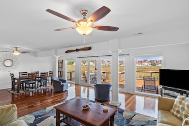 Living room featuring decorative columns, wood finished floors, a ceiling fan, and french doors