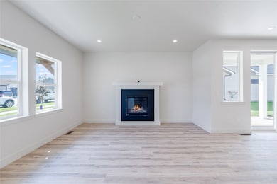 Unfurnished living room featuring light wood finished floors, recessed lighting, and a glass covered fireplace