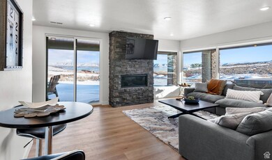 Living area with a stone fireplace, light wood-style flooring, plenty of natural light, a textured ceiling, and recessed lighting