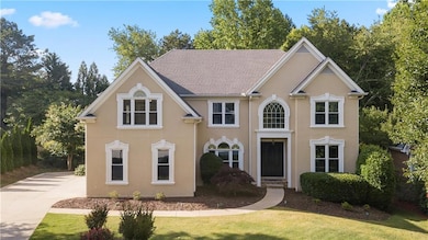 View of front of home with stucco siding, a front yard, and driveway