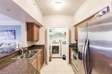 Kitchen with stainless steel appliances, washer and clothes dryer, light tile patterned floors, and brown cabinetry