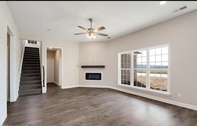 Unfurnished living room featuring ceiling fan, a glass covered fireplace, stairs, dark wood-style flooring, and recessed lighting