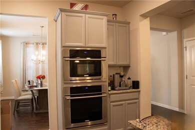 Kitchen featuring double oven, a chandelier, dark wood finished floors, and light countertops