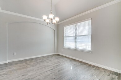 Empty room featuring lofted ceiling, a notable chandelier, crown molding, and light wood-type flooring