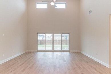 Empty room featuring a high ceiling, ceiling fan,