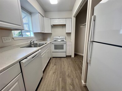Kitchen with white appliances, white cabinetry, light countertops, and dark wood-style floors