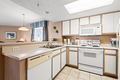Kitchen with white appliances, a sink, a peninsula, a textured ceiling, and light countertops