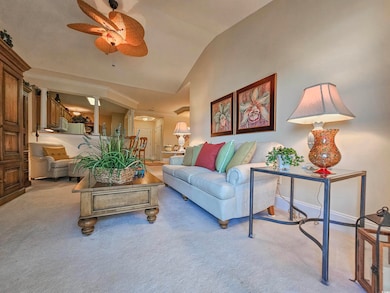 Living area featuring vaulted ceiling, ceiling fan, and carpet floors