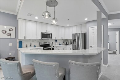 Kitchen featuring crown molding, stainless steel appliances, white cabinets, hanging light fixtures, and light stone countertops