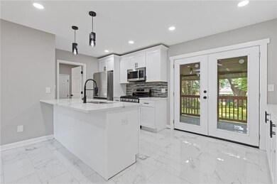 Kitchen featuring stainless steel appliances, a sink, french doors, white cabinetry, and baseboards