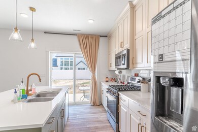 Kitchen featuring appliances with stainless steel finishes, light countertops, backsplash, light wood-style flooring, and recessed lighting
