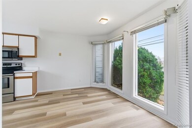 Kitchen with brown cabinets, light countertops, stainless steel appliances, light wood-style floors, and white cabinetry
