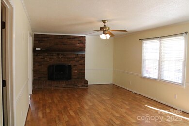 Living room featuring laminate wood flooring, ceiling fan and a beautiful brick fireplace 