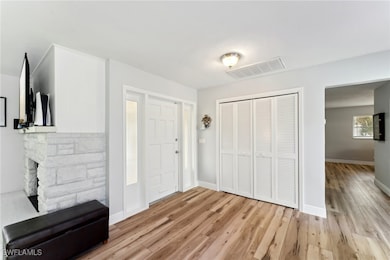 Foyer entrance featuring a stone fireplace and lig