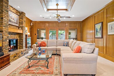 Very large living room off the foyer featuring a brick fireplace and a wall of windows overlooking the back patio.