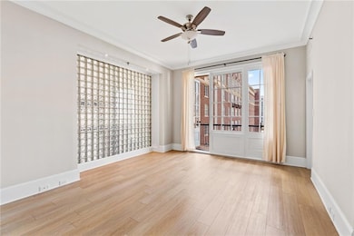 Spare room featuring ceiling fan, light wood-type flooring, and crown molding